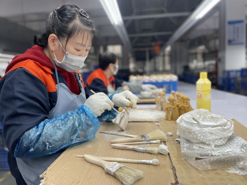 53岁的周萍在彩绘车间，用刷子麻利地将彩绘涂抹在一对小天使的身上。.jpg